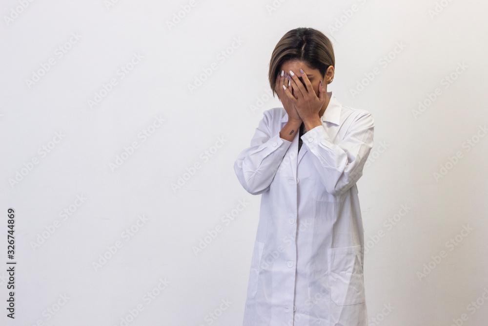 Portrait of sad latin young woman model covered her face with her hands. Pharmacist, beauty therapist, doctor, veterinarian, scientist, optometrist, isolated on white background studio shot, in white Portrait of sad latin young woman model covered her face with her hands. Pharmacist, beauty therapist, doctor, veterinarian, scientist, optometrist, isolated on white background studio shot, in white
