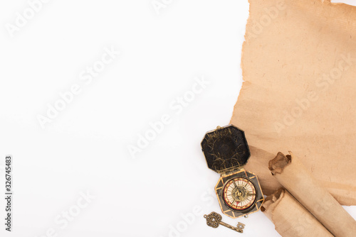 top view of vintage compass, key and aged parchment paper isolated on white
