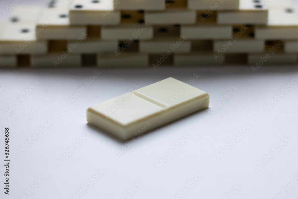 Empty domino bone close-up lies next to the stairs made of domino bones on a light background and place for text Empty domino bone close-up lies next to the stairs made of domino bones on a light background and place for text