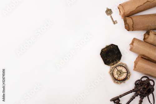 top view of vintage compass, keys and aged parchment paper isolated on white