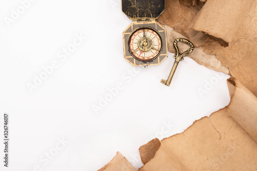 top view of vintage key, compass and aged paper isolated on white