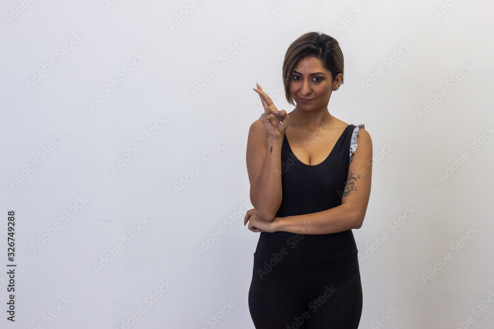 Portrait of gymnast, young woman modelwith a golf club keeping finger crossed, having calm expression, isolated on white background studio shot, white t-shirt, dark air. Place for your text in copy sp Portrait of gymnast, young woman modelwith a golf club keeping finger crossed, having calm expression, isolated on white background studio shot, white t-shirt, dark air. Place for your text in copy sp