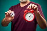 Man in t-shirt holding egg and alarm clock. Eggs cooking