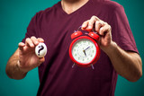 Man in t-shirt holding egg and alarm clock. Eggs cooking