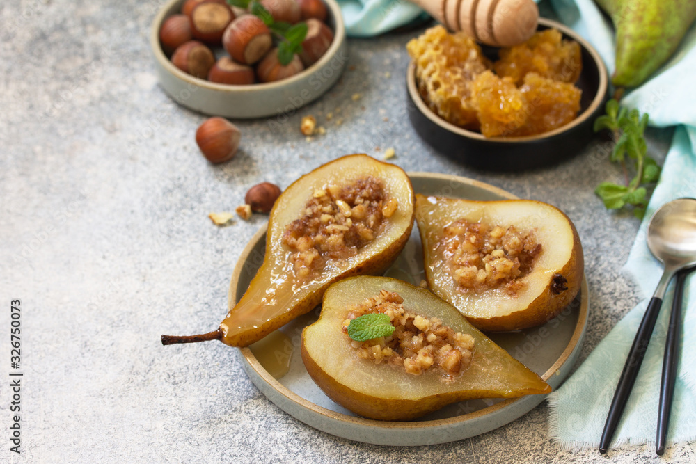 Healthy diet dessert. Baked pears with hazelnuts, honey and granola on a slate, stone or concrete background. Copy space. Healthy diet dessert. Baked pears with hazelnuts, honey and granola on a slate, stone or concrete background. Copy space.