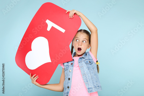 Young girl holding paper card with heart and number one on blue background