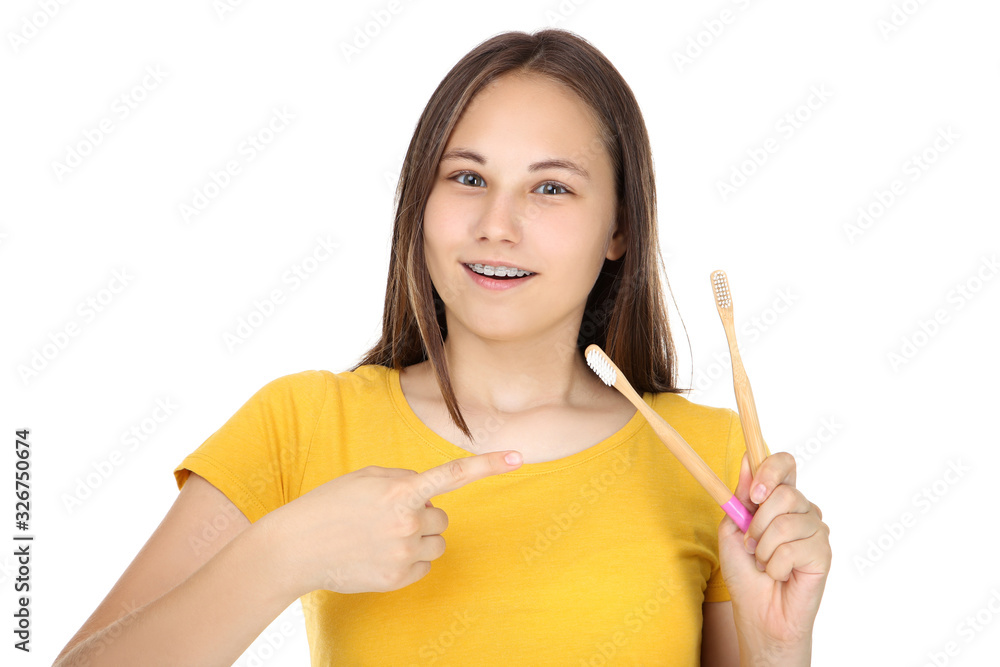 Young girl with dental braces holding toothbrushes on white background Young girl with dental braces holding toothbrushes on white background