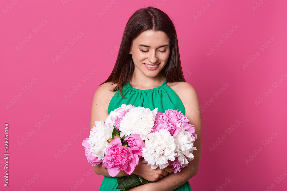 Beautiful cheerful girl stands smiling and holding bouquet of white and pink flowers. Young happy woman in sundress enjoying her present from boyfriend for 8 march. International Women's Day concept.