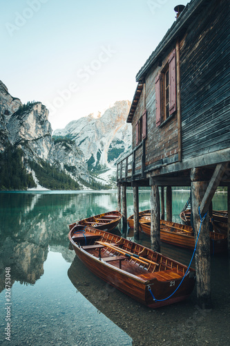 Fototapeta Naklejka Na Ścianę i Meble -  Traditional wooden rowing boat on scenic Lago di Braies in the Dolomites in scenic morning light at sunrise, South Tyrol, Italy	Beautiful reflections.  Peaceful and calming scene