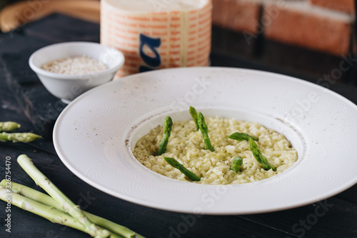 Risotto with asparagus in white plate on a black wooden table. View from above.