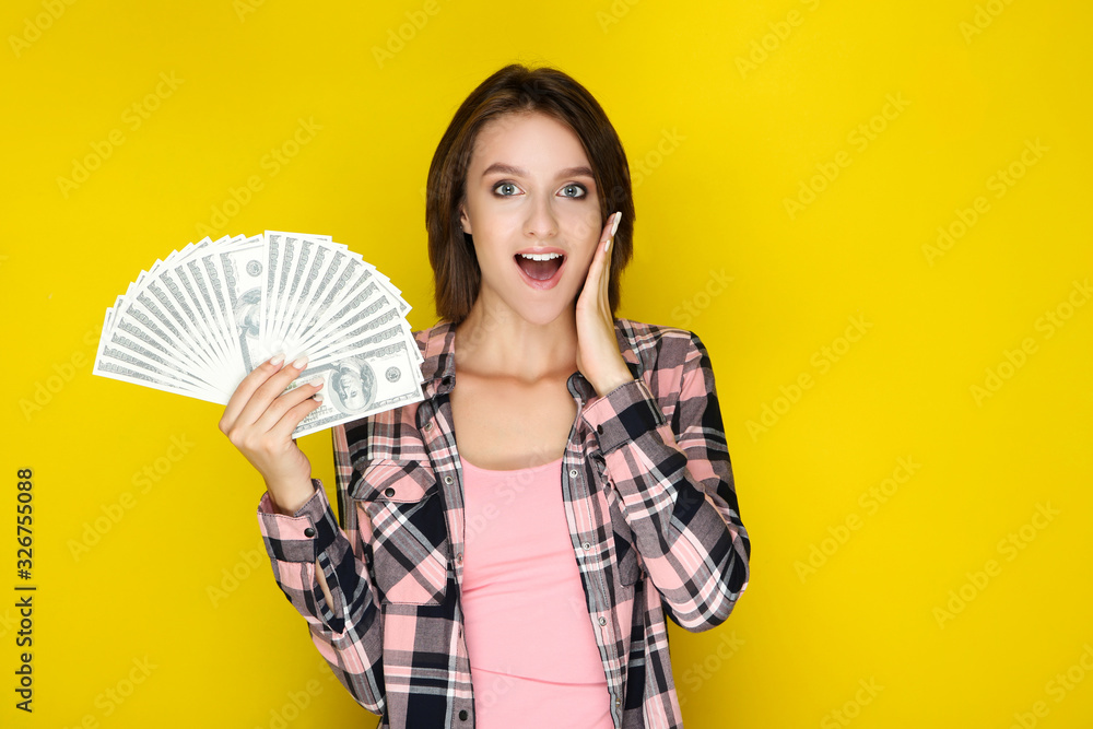 Young woman holding dollar banknotes on yellow background Young woman holding dollar banknotes on yellow background