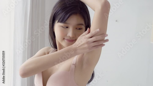 Beautiful young asian woman in underwear applying cream and lotion on armpit, beauty girl is slim happy touch skin armpit and hair removal for body care, treatment and cosmetic and cleaning. photo