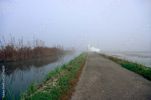 Road and water channel towards the infinity of fog.