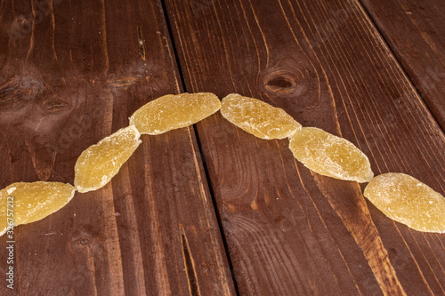 Group of six slices of dried yellow pineapple on brown wood photo