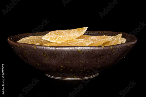 Lot of slices of dried yellow pineapple in glazed bowl isolated on black glass photo