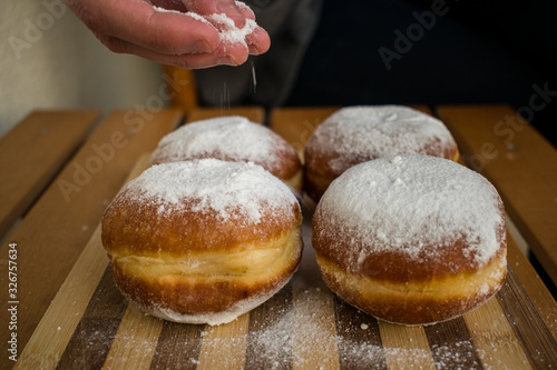 Woman hand sprinkle with powdered sugar homemade donuts
