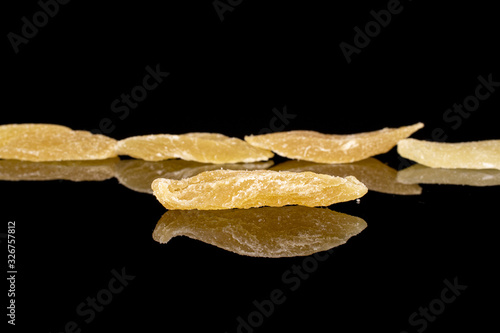 Group of five slices of dried yellow pineapple isolated on black glass photo