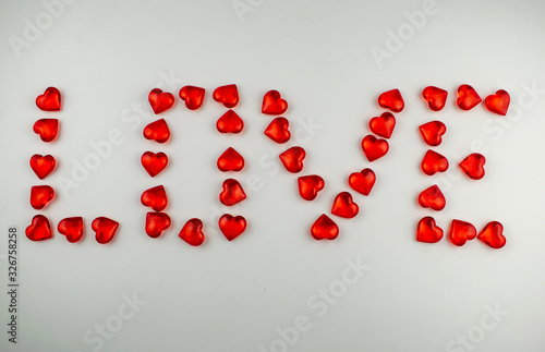 Love inscription made of crystal hearts on a white background.