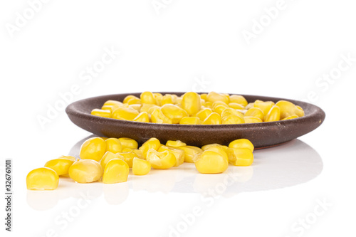 Lot of pieces of bright canned yellow corn with brown ceramic coaster isolated on white background