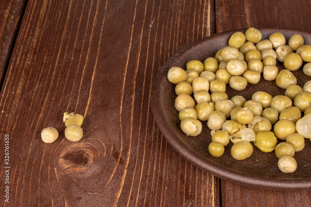 Lot of whole canned pea with brown ceramic coaster on brown wood