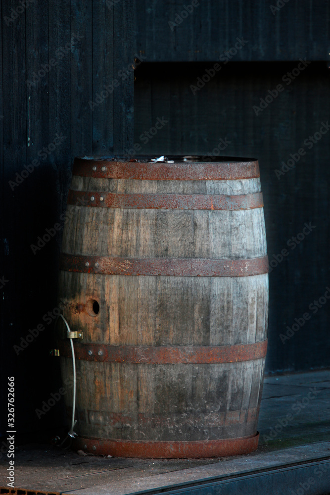old wooden barrel with rusty hoops against a dark wall old wooden barrel with rusty hoops against a dark wall