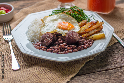Brazilian food dish. Beans, rice, egg, salad and potatoes. Rustic wood background