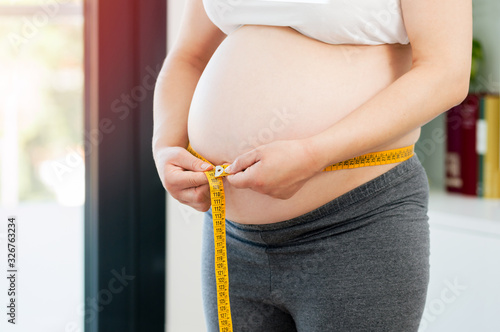 pregnant woman measuring her belly at home