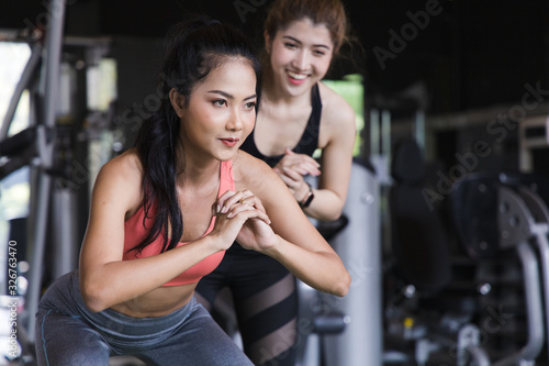 Portrait of a group of young asian fit people cheering on their friends Squats in fitness gym