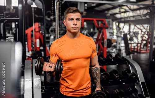 Fit young man working out with dumbbells at the gym