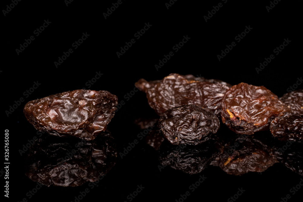 Lot of whole dried dark raisin isolated on black glass Lot of whole dried dark raisin isolated on black glass
