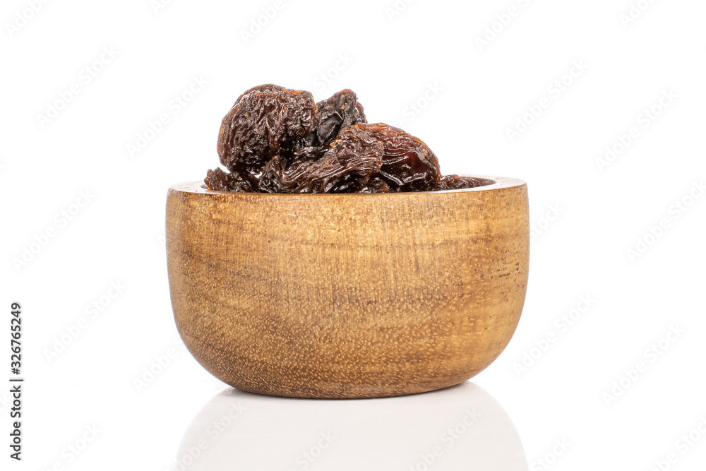Lot of whole dried dark raisin in bamboo bowl isolated on white background Lot of whole dried dark raisin in bamboo bowl isolated on white background