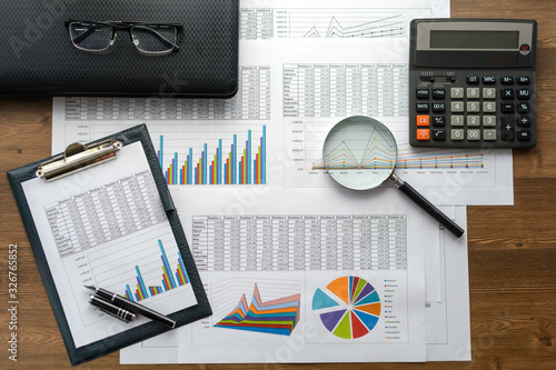 Financial documents - graphics, statistics, drawings, keyboard, laptop, magnifying glass in the office. Business, science, long hours of work.