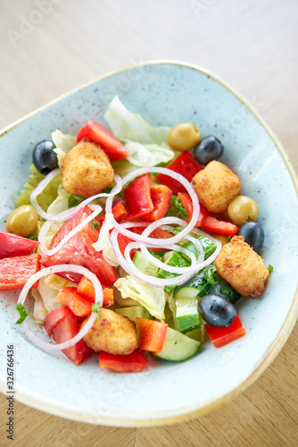 Traditional greek salad with fresh vegetables, feta cheese and olives. Wooden table in restaurant