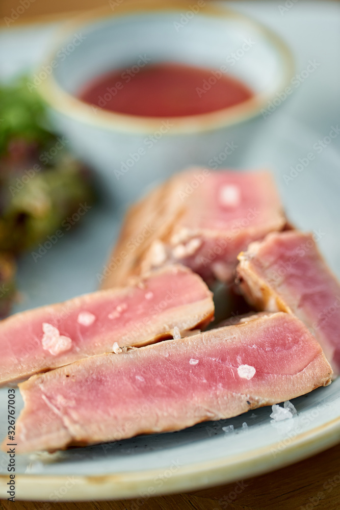 Closeup Medium rare tuna with lettuce and hot sauce. Restaurant menu Closeup Medium rare tuna with lettuce and hot sauce. Restaurant menu