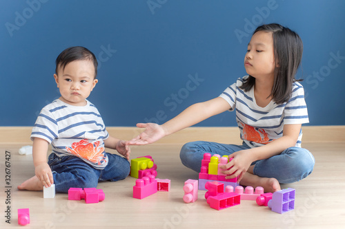 Portrait of asian baby boy and older sister quarrel about toys.concept kids sharing.