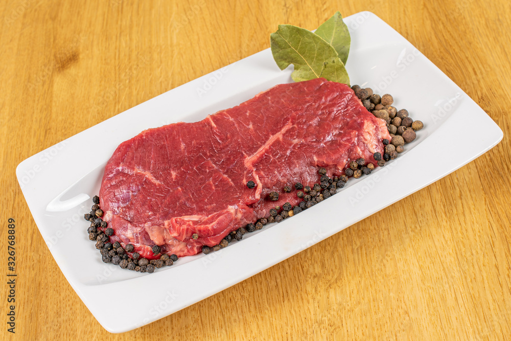 Beautiful raw beef sirloin with spices on white rectangular ceramic plate on lacquered wood Beautiful raw beef sirloin with spices on white rectangular ceramic plate on lacquered wood