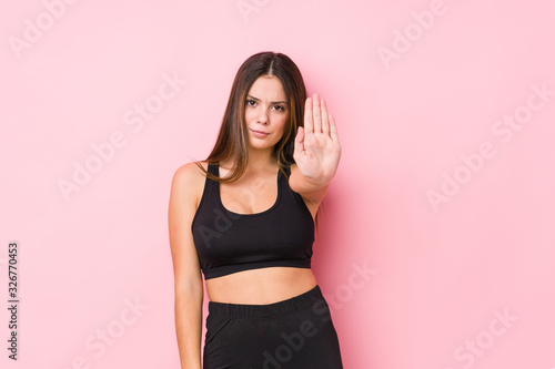 Young fitness caucasian woman isolated standing with outstretched hand showing stop sign  preventing you.