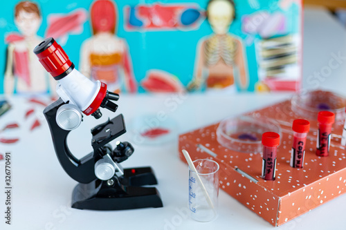 Fotografi school concept, toy microscope stands on a table, coronovirus test tubes, option