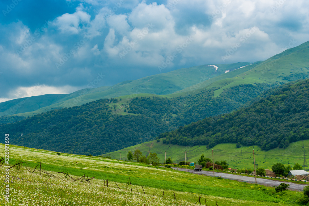 Blue clouds push by green picturesque mountains of the Caucasus, landscape of Armenia