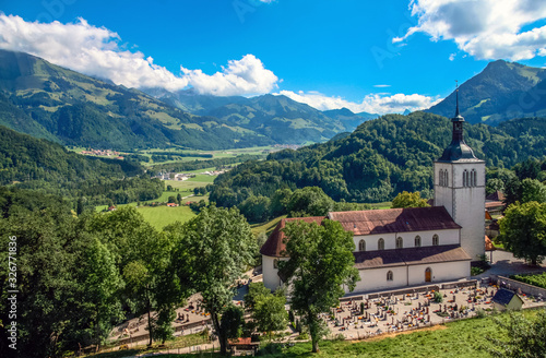 Gruy  res  Canton of Fribourg   Switzerland - August 5th  2008  The Saint Theodule Church and its cemetery as seen from the Chateau de Gruy  res  with the Sarine Saane Valley in the background