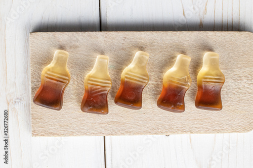 Group of five whole sweet jelly cola on wooden cutting board flatlay on white wood