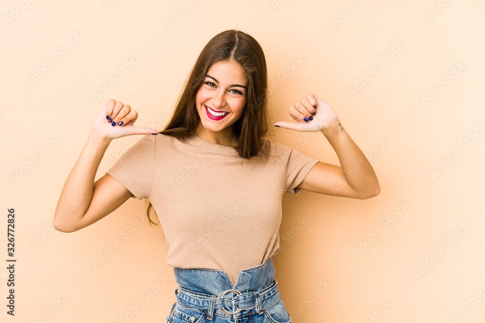 Young caucasian woman isolated en beige background feels proud and self confident, example to follow. Young caucasian woman isolated en beige background feels proud and self confident, example to follow.