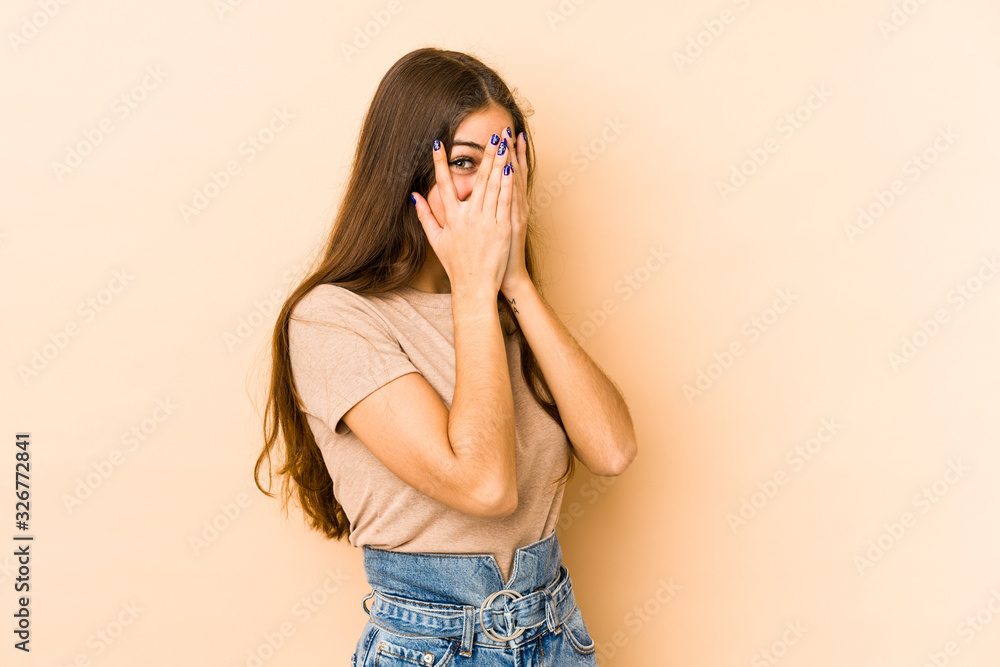 Young caucasian woman isolated en beige background blink through fingers frightened and nervous. Young caucasian woman isolated en beige background blink through fingers frightened and nervous.