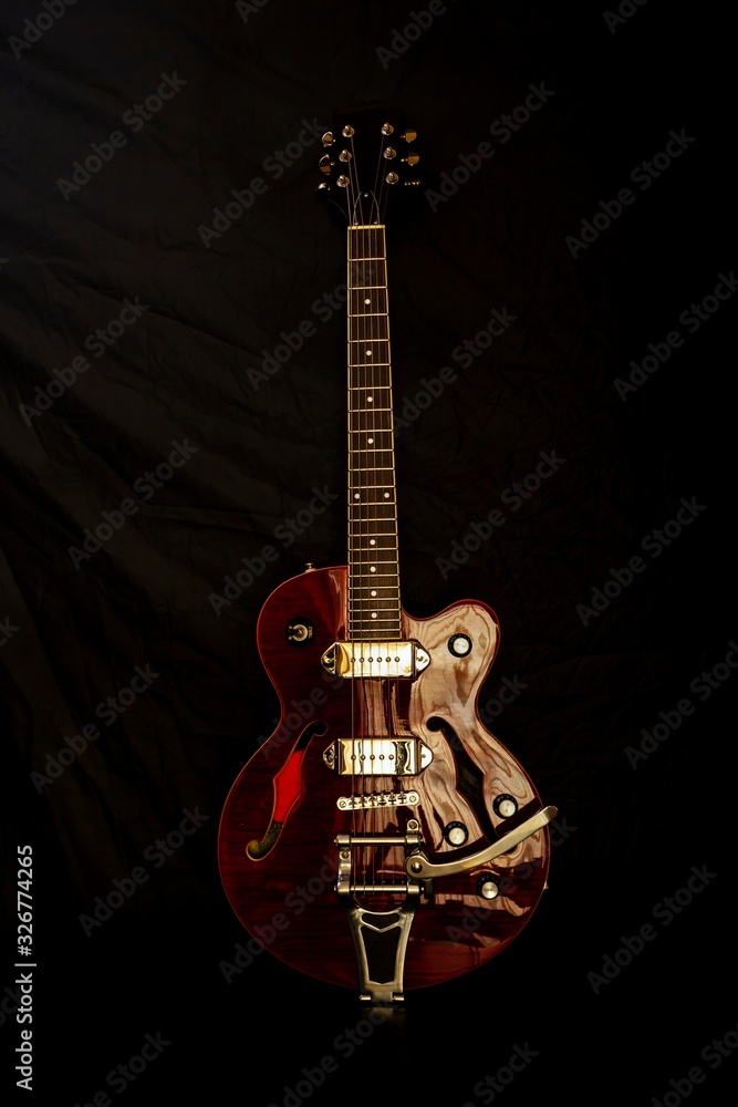 Obraz premium Electric guitar with semi-acoustic body on black background.