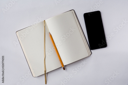 An opened note book with a bookmark, smartphone and a pencil isolated on grey background. Preparation for the business meeting.