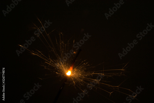 I hold a sparkler in my hand  which sparkles beautifully in different directions.