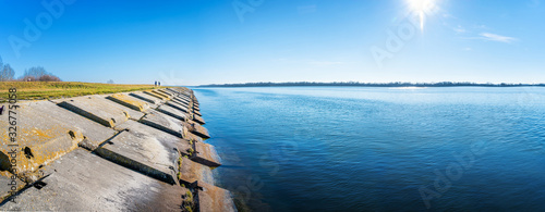 Gabcikovo Dam with bank made of concrete blocks on sunny day - panoramic photo