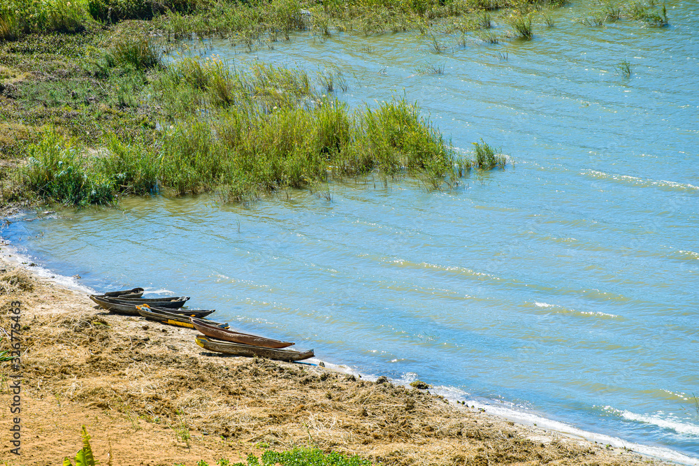Canoes await fishermen from the bay on the sand of the calm beach covered with vegetation Canoes await fishermen from the bay on the sand of the calm beach covered with vegetation