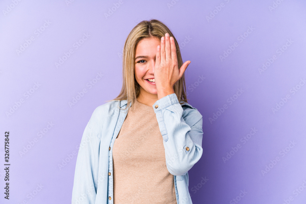 Young blonde caucasian woman isolated having fun covering half of face with palm. Young blonde caucasian woman isolated having fun covering half of face with palm.