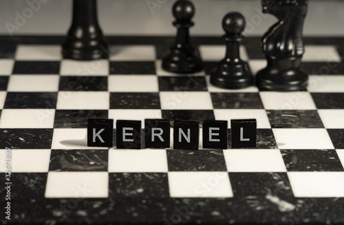 The concept of Kernel represented by black and white letter tiles on a marble chessboard with chess pieces photo